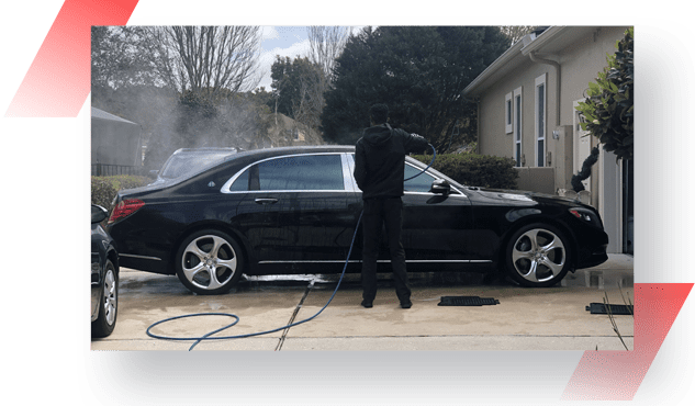 A man is washing his car with a hose.