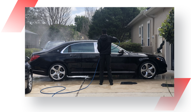 A man is washing his car with a hose.