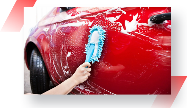 A person cleaning the side of a red car.