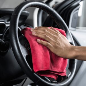 A person cleaning the steering wheel of their car.