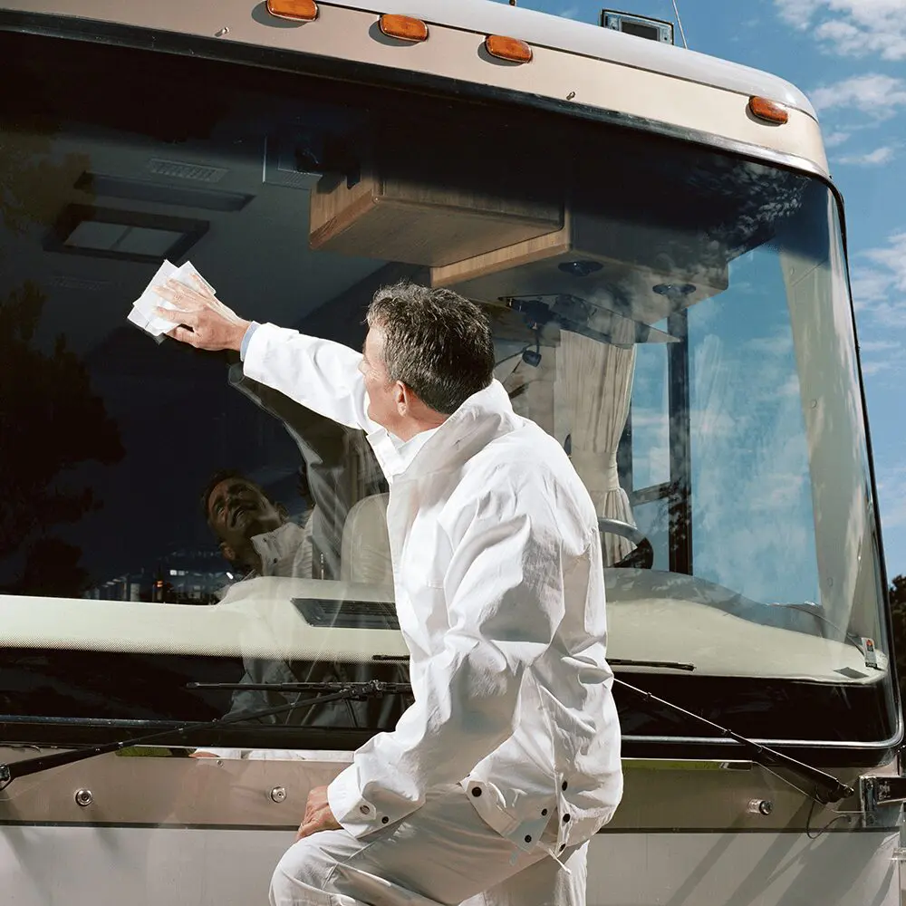 A man in white is standing next to a bus.